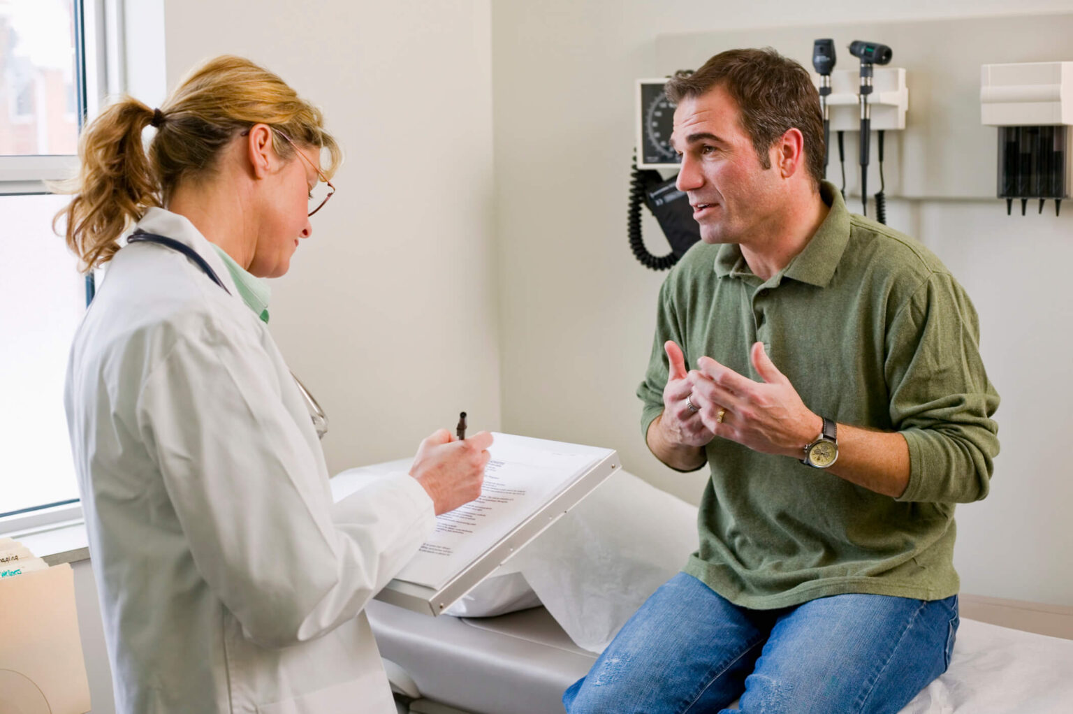 Male patient in exam room talking to doctor.